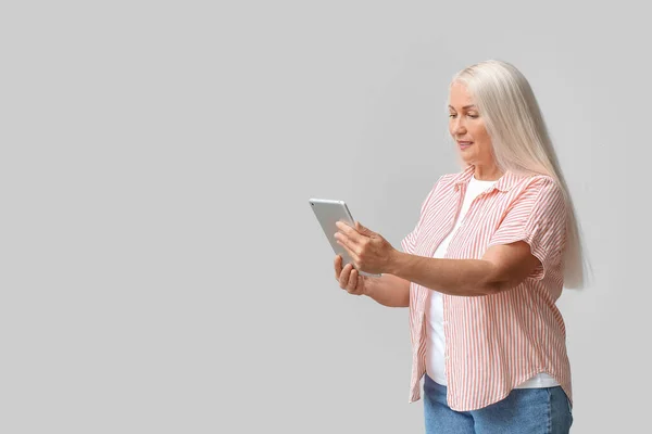 Зрелая Женщина Использует Планшетный Компьютер Навигации Светлом Фоне — стоковое фото