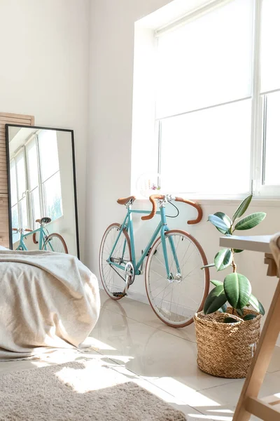 Modern bicycle near window in light bedroom