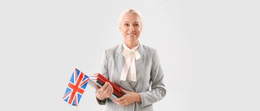 Female English teacher with books and UK flag on light background