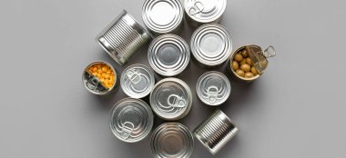 Many tin cans with food on grey background, top view