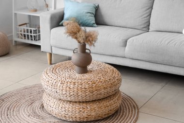 Vase with pampas grass on rattan poufs in living room