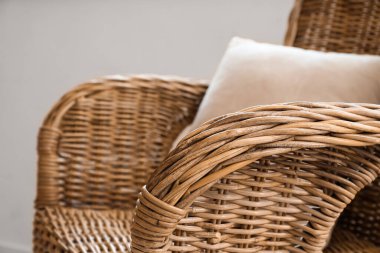 Rattan armchair with cushion in light room, closeup