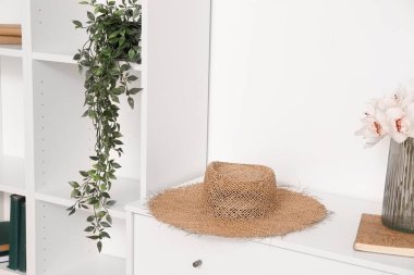 Stylish hat on chest of drawers near light wall