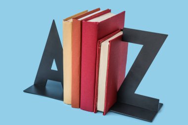 Stylish stand with books on blue background