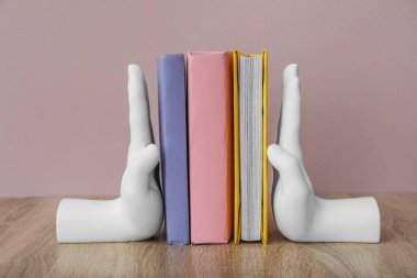 Stylish holder with books on table near pink wall