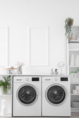 Interior of light laundry room with washing machines and shelving units