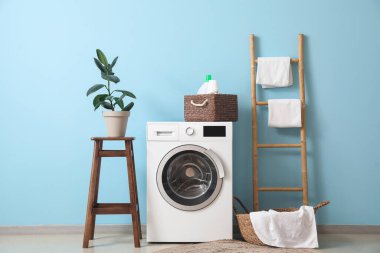 Interior of stylish laundry room with washing machine, stool and ladder