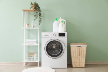 Interior of stylish laundry room with washing machine, shelving unit and basket