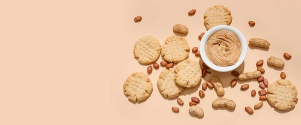 stock image Tasty peanut cookies and bowl of butter on beige background with space for text