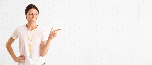 Female Physical Education Teacher Pointing Something White Brick Background — Stock Photo, Image