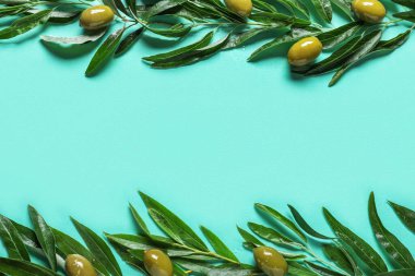 Frame made of green olives and leaves on blue background
