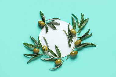 Blank paper sheet with green olives and leaves on blue background