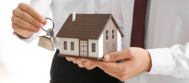 Couple with model of house and key, closeup. Concept of buying property