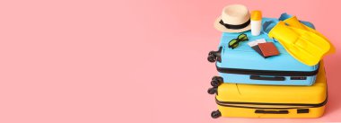 Suitcases and beach accessories on pink background with space for text