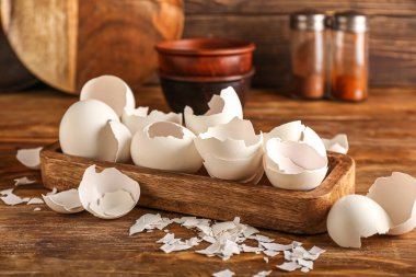 Board with cracked egg shells on wooden background