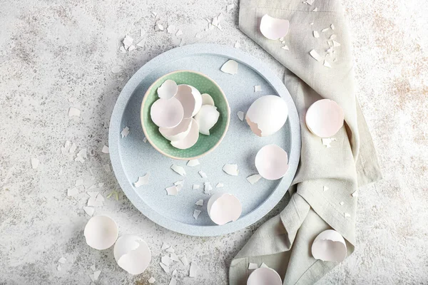 Tray with bowl of broken egg shells on grunge background