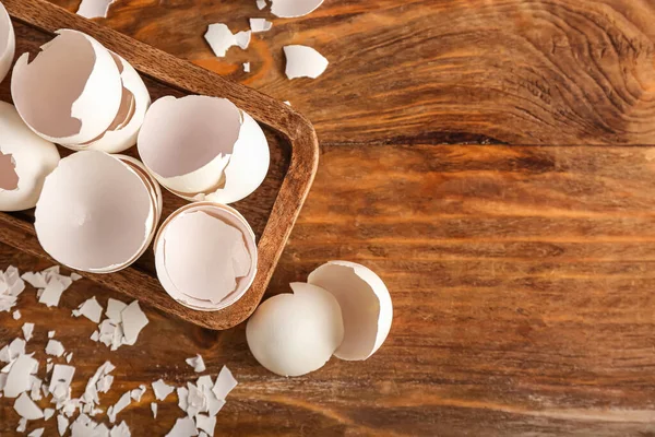 Board with cracked egg shells on wooden background