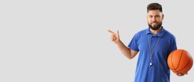 Portrait of male PE teacher pointing at something on light background with space for text