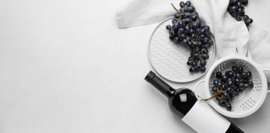 Bottle of red wine with fresh grapes on white background with space for text