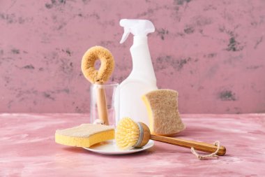 Different cleaning supplies and spray bottle on color table