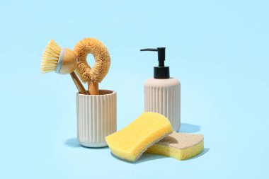 Set of cleaning supplies and pump bottle on blue background