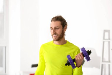 Sporty young man using dumbbells in gym