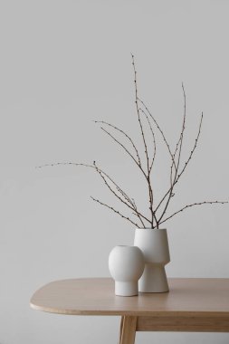Vases with branches on table in room