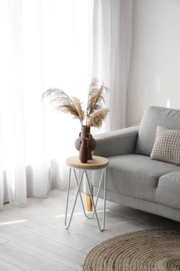 Pencerenin yanında kanepesi ve masası olan modern oturma odası.