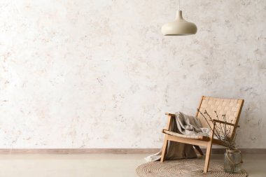 Armchair and vase with branches in light room