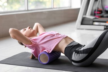 Spor salonunda köpük silindirli genç kadın eğitimi.