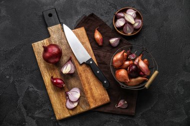 Composition with wooden board of red onion on dark background