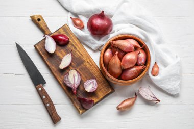 Composition with fresh red onion and knife on light wooden background