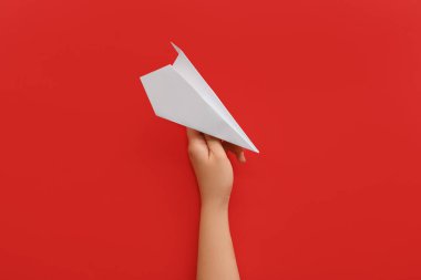 Woman with white paper plane on red background