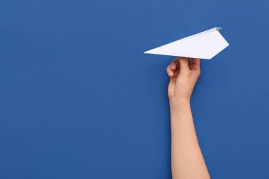 Woman with white paper plane on blue background