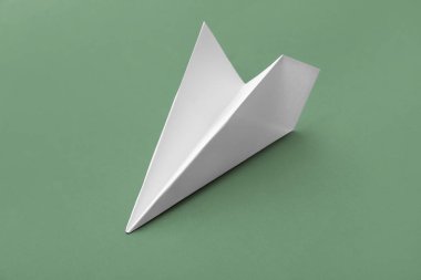 White paper plane on green background
