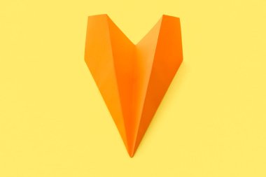 Orange paper plane on yellow background