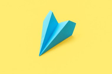 Blue paper plane on yellow background