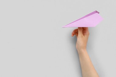 Woman with lilac paper plane on grey background