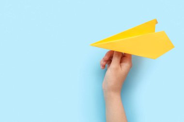 Woman with yellow paper plane on blue background