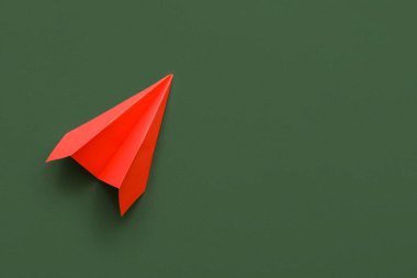 Red paper plane on green background