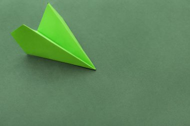 Green paper plane on color background