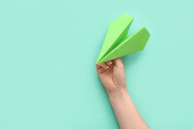 Woman with green paper plane on color background