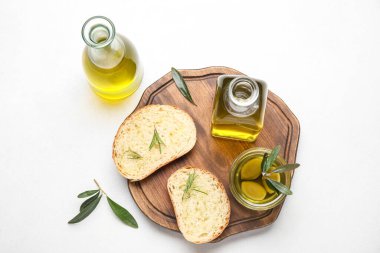 Composition with bottles of fresh olive oil and bread on light background
