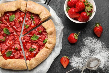 Composition with sweet galette and strawberry on dark background, closeup