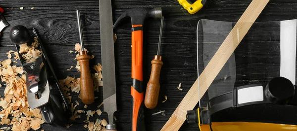 Set of carpenter's tools on dark wooden background, top view