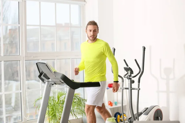 Sporty young man using step machine in gym