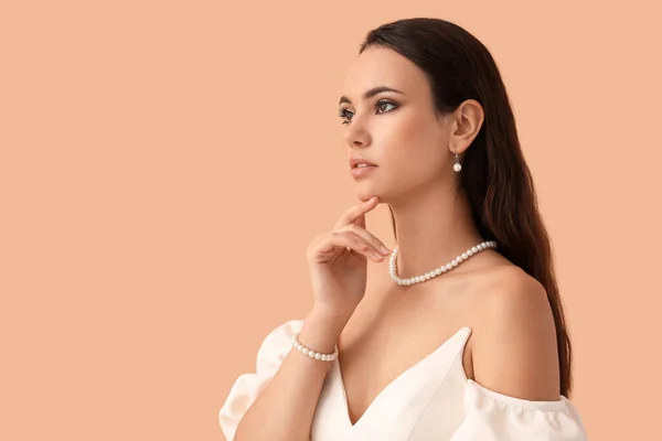 Beautiful Young Woman Stylish Pearl Jewelry Beige Background — Stockfoto