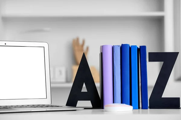 Stylish holder with books and laptop on table in room