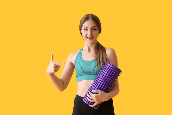 Young Woman Pointing Purple Foam Roller Yellow Background — Stock fotografie