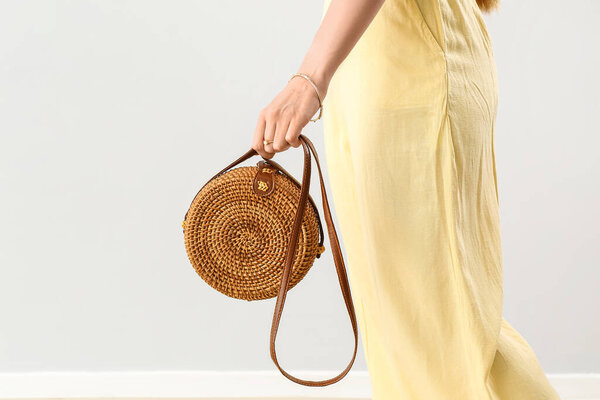 Elegant woman with stylish rattan handbag on light background, closeup